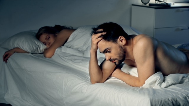 Man lying awake in bed staring at the nothing, unable to sleep